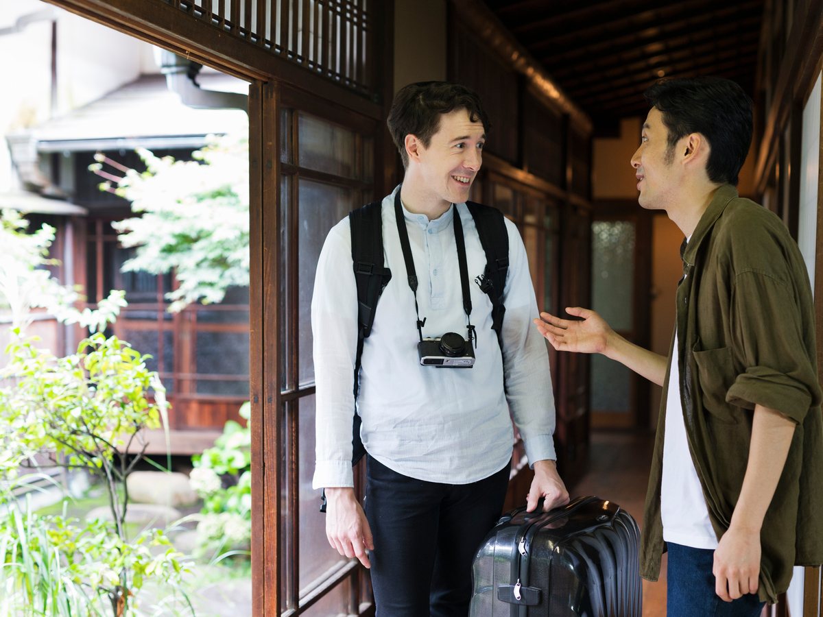 旅館のスタッフが外国人のお客様を出迎えて案内している様子